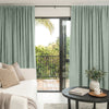 Sage green Alder Faux Linen Blackout Curtain with texture, blocking light in a living room.